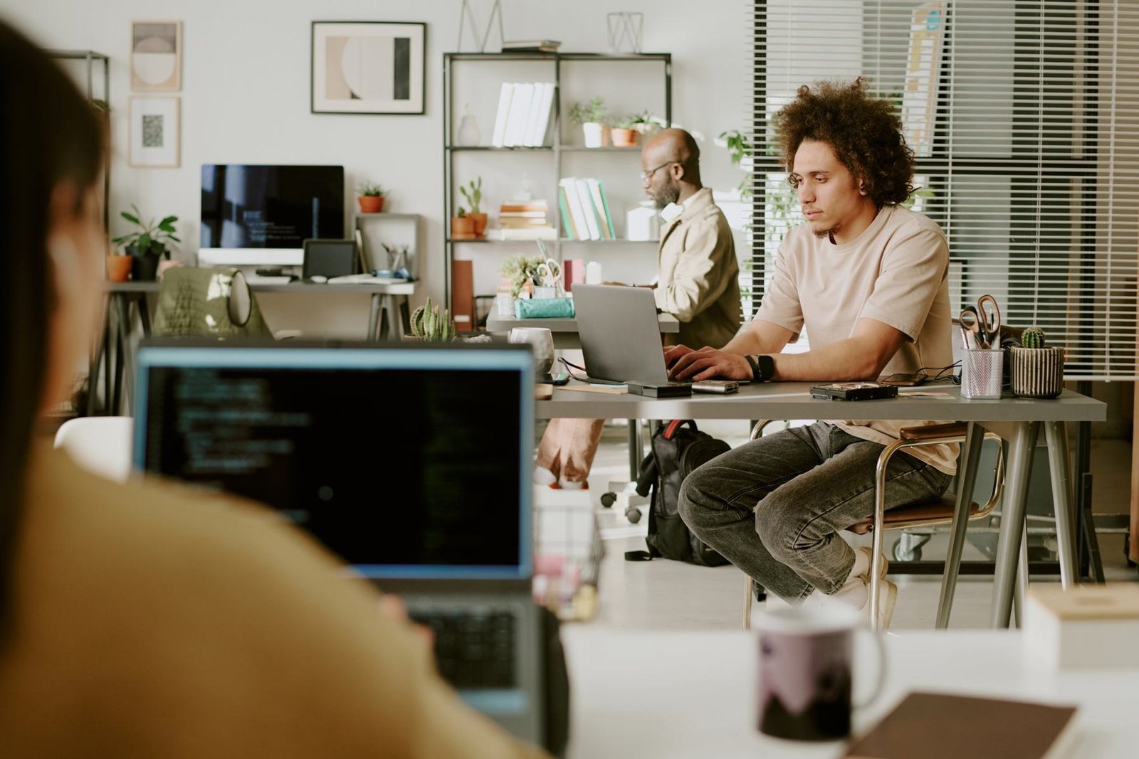 Two people working at laptops in a studio